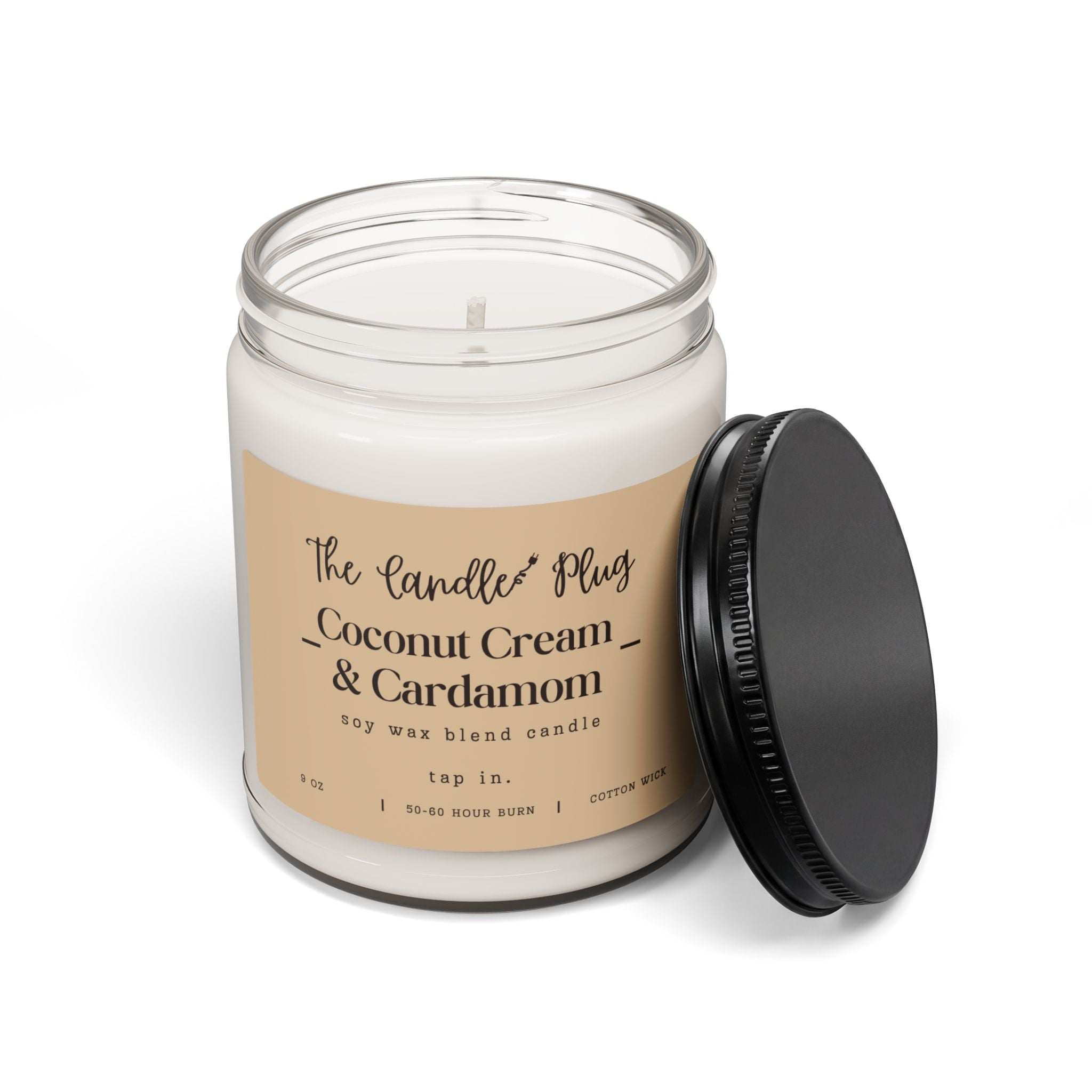 A Coconut Cream and Cardamom soy candle with white wax in a clear glass jar, a beige label reading 'The Candle Plug Coconut Cream & Cardamom', and a black screw-on lid leaning against the jar on a white background.