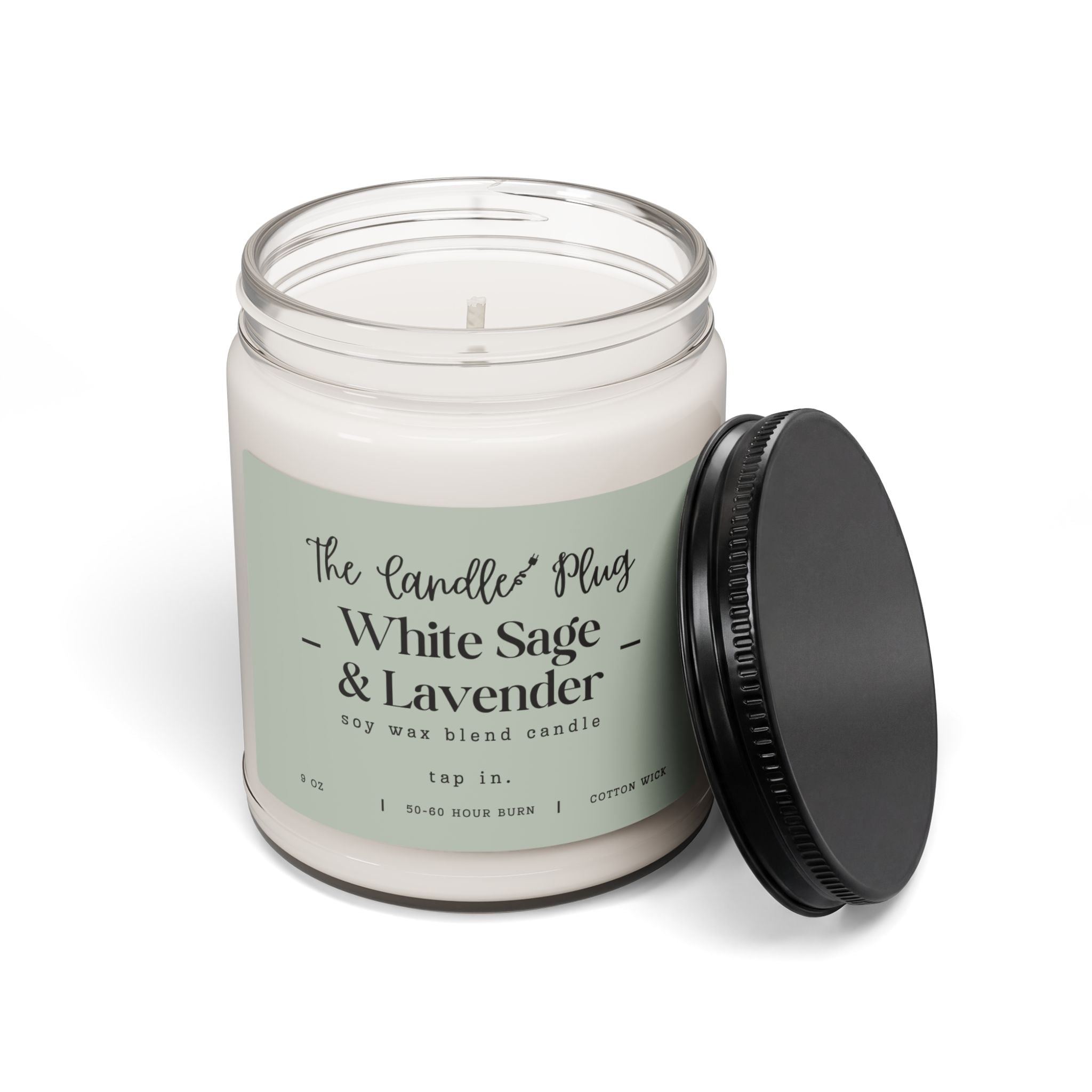 A White Sage and Lavender soy candle in a clear glass jar with a pale sage green label reading 'The Candle Plug - White Sage & Lavender,' shown with a black screw-top lid leaning against the jar on a white background.