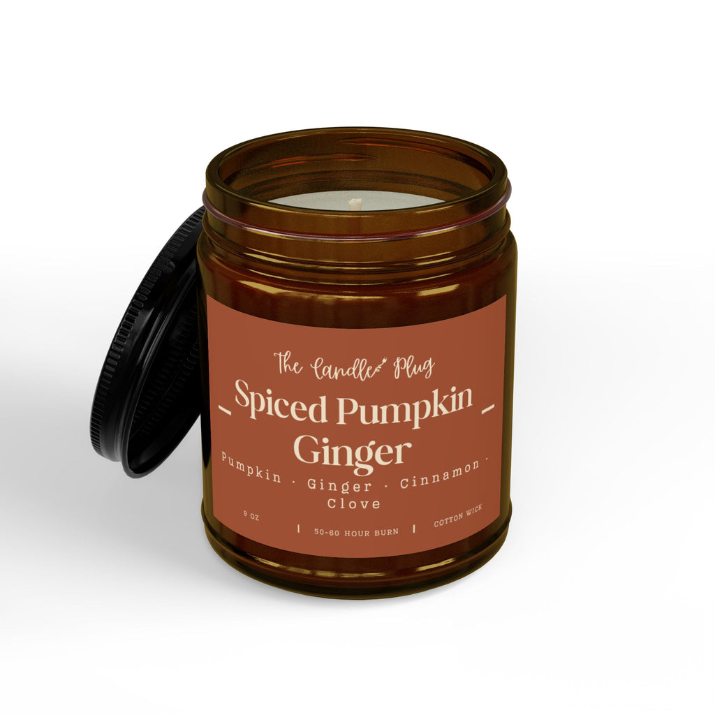 An amber glass jar candle with a black lid leaning against it, featuring a terracotta label that reads 'The Candle Co Spiced Pumpkin Ginger' on a clean white background.